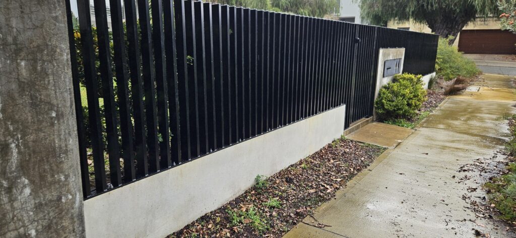 Precision-engineered steel batten gate in Night Sky finish, FencrGatr® Swanbourne project, pet-safe design. Completed Swanbourne steel batten fence and gate by FencrGatr®, perfectly levelled to varying wall heights, pet-safe